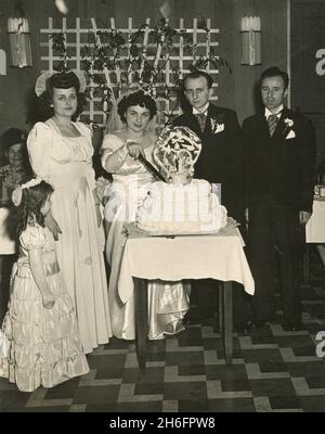 Photos d'un mariage américano-italien des années 1940: Mariée et marié avec des demoiselles d'honneur et meilleur homme à la coupe de gâteau Banque D'Images