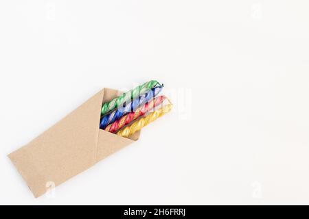 Bougies colorées jaune, rouge, bleu et vert étincelantes, conditionnées en papier brun artisanal.Isolé sur fond blanc avec espace de copie pour te personnalisé Banque D'Images