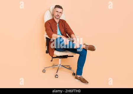 Photo pleine grandeur de l'économiste de banque intelligent Guy sit chaise en cuir ont conférence de partenariat isolé sur fond beige couleur Banque D'Images