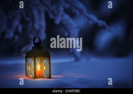 Lanterne aux chandelles dans la neige au crépuscule.Noël dans un jardin d'hiver. Banque D'Images