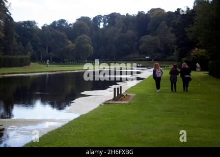Personnes marchant le long de l'étang à Studley Royal Water Gardens, Parc royal de Studley, Abbaye de Fountains, Aldfield, près de Ripon, North Yorkshire, Angleterre Banque D'Images