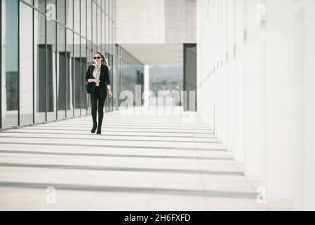 Une jeune femme d'affaires se promène à l'extérieur du bâtiment d'entreprise Banque D'Images