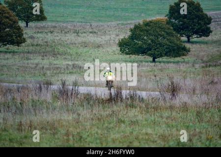 Un motard (motard) dans une veste jaune haute visibilité à bord de sa moto le long d'une piste de pierre sur Salisbury Plain, Wiltshire Banque D'Images