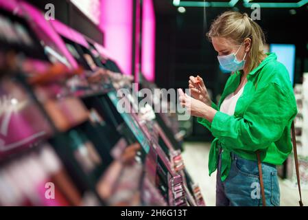 Femme essayant des produits cosmétiques dans le magasin de cosmétiques. Banque D'Images