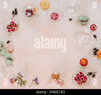 Cadre d'ornements bricolés remplis de fleurs séchées sur fond de béton beige avec espace vide pour le texte.Idée de décoration d'arbre de Noël ou de Saint-Valentin. Banque D'Images