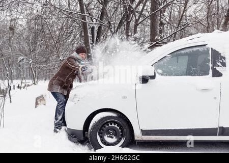 Une femme qui nettoie sa voiture après de fortes chutes de neige Banque D'Images