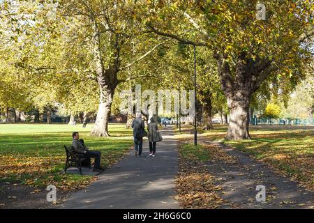 Les gens qui apprécient la journée d'automne ensoleillée dans le parc London Fields à Hackney, Londres Angleterre Royaume-Uni Banque D'Images