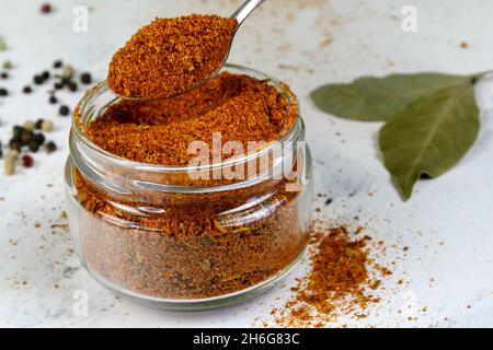 Chef prenant avec une cuillère à café d'épices poivre rouge moulu ou piment dans un pot à épices en verre, pour préparer des aliments savoureux et savoureux.Mise au point sélective.Gros plan. Banque D'Images