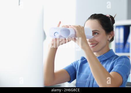 La jeune femme regarde à travers des jumelles en papier Banque D'Images