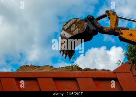 Excavatrice orange chargeant le sol dans un camion de benne sur le chantier .Creusez dans la zone agricole.Photo de haute qualité Banque D'Images