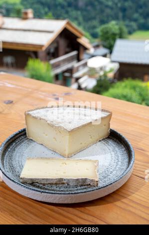 Collection de fromages, tomme de savoie et village de montagnes françaises en haute-Savoie en été en arrière-plan Banque D'Images