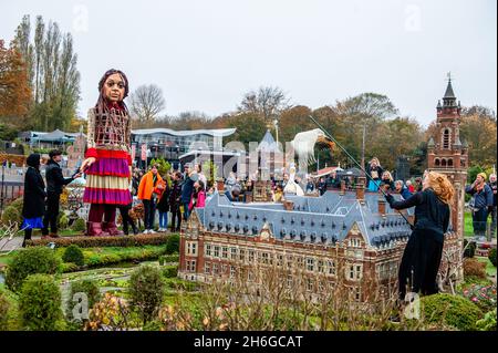 Little Amal est vu à la recherche d'une marionnette d'un oiseau volant au-dessus du bâtiment miniature du Palais de la paix.Amar, un nouveau centre culturel dans le centre de la Haye a organisé dans le cadre de son 'Open Festival', la visite de la marionnette géante 'Little Amal',Une jeune fille syrienne de neuf ans et plus de 11 mètres de hauteur jusqu'au parc miniature Madurodam.Elle est invitée à participer au Festival en tant qu'invitée spéciale dans la ville pour attirer l'attention à travers l'Europe sur le sort des jeunes réfugiés qui ont fui la Syrie.Amal a été reçu à l'extérieur du parc par un groupe d'enfants, après qu'elle a pu marcher autour de la 1:2 Banque D'Images