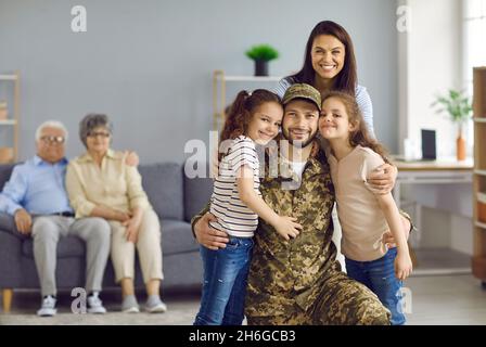 Bonne femme et enfants embrassant leur père vétéran qui est revenu de l'armée Banque D'Images