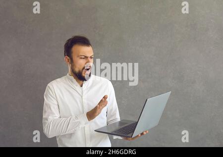 Un homme caucasien outragé, perplexe, regarde l'écran d'un ordinateur portable et fait un geste de refus en disant non Banque D'Images