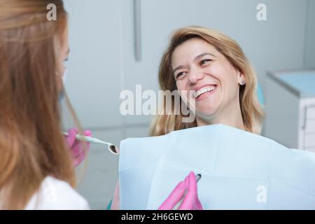 Bonne femme mûre riant, parlant à son dentiste pendant un rendez-vous dentaire Banque D'Images