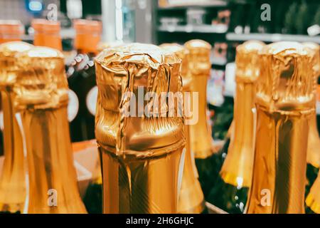 Beaucoup de bouteilles de champagne en magasin.Vente de boissons alcoolisées avant les vacances.Gros plan des goulots d'étranglement. Banque D'Images