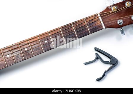 Guitare acoustique classique et capo sur fond blanc, gros plan. Banque D'Images