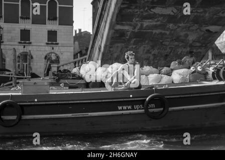 Jeune homme travaillant sur une barge de livraison USP à travers les canaux de Venise Banque D'Images