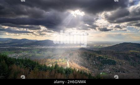 Le soleil brille à travers les nuages sur une route dans la forêt noire Banque D'Images