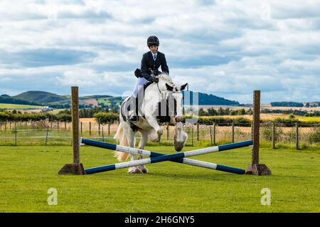 Spectacle équestre d'été avec une jeune fille à cheval sautant un cheval, East Lothian, Écosse, Royaume-Uni Banque D'Images