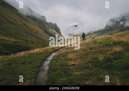 L'homme s'arrête sur le sentier pour admirer les montagnes des Pyrénées par une journée nuageux. Banque D'Images