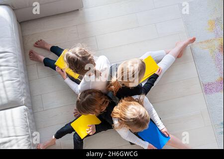 Quatre enfants sur le sol dans la salle de séjour font du travail de préparation pour l'école.Apprendre ensemble. Banque D'Images