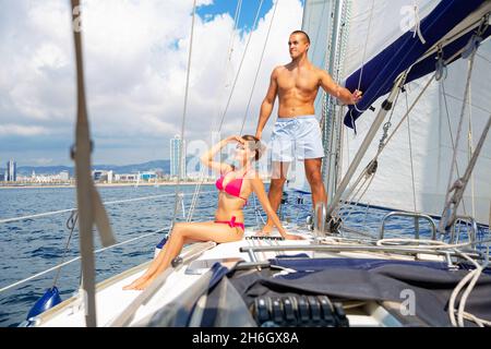 Jeune couple aimant profiter de sortie en mer sur voilier de plaisance le long de la côte de Barcelone le jour d'été ensoleillé Banque D'Images