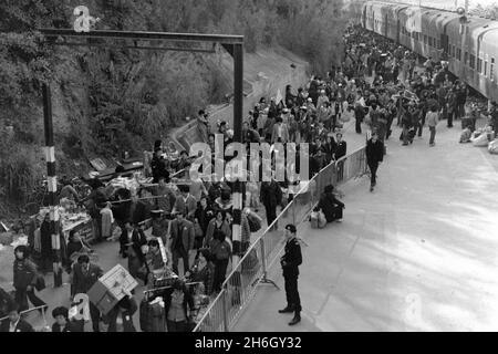 Gare de Lo Wu, Hong Kong. Vue depuis le toit de la gare - vue au sud - des passagers sortant d'un train, en direction de la Chine continentale à l'année lunaire du nouvel an, 1981. Beaucoup portent des cadeaux pour des parents, en utilisant des yokes de bambou pour équilibrer leurs colis. Les trains diesel ont été progressivement éliminés lorsque le chemin de fer Kowloon-Canton (section HK) a été électrifié au début de 1980s Banque D'Images