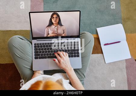 Vue de dessus vers le bas chez une jeune femme méconnaissable utilisant un ordinateur portable tout en étudiant en ligne à la maison Banque D'Images