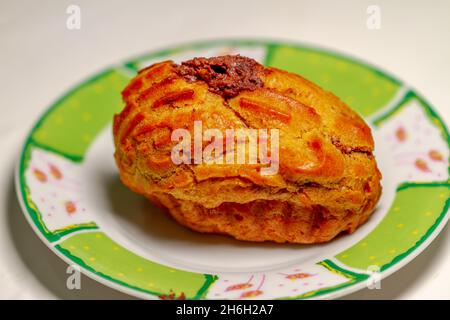 Un gâteau circulaire aux profiteroles, servi sur une petite assiette, pour le petit déjeuner ou un menu avec café Banque D'Images