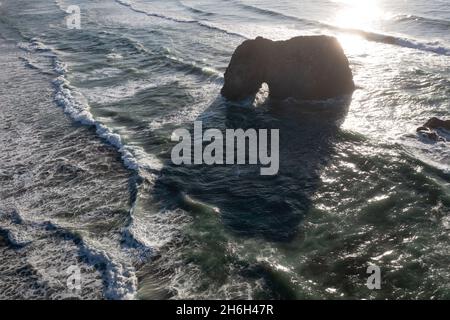 La lumière du soleil brille à travers une arche naturelle qui se trouve au large de la côte sauvage de la Californie du Nord, non loin au nord de fort Bragg. Banque D'Images