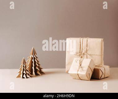 Sapin de Noël en papier artisanal de cadeaux d'origami emballé dans le papier ordinaire étoile en bois sur un fond beige tendance. Banque D'Images