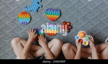 Vue d'en haut jusqu'aux enfants jouant avec des jouets pop IT.Bonne enfance Banque D'Images