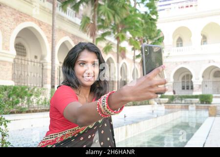 Belle femme indienne asiatique souriant et utilisant un téléphone pour prendre un autoportrait. Banque D'Images