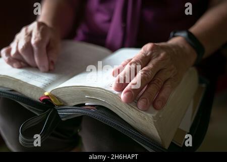 Femme âgée froissée la main sur un livre ouvert.Vue rapprochée. Banque D'Images