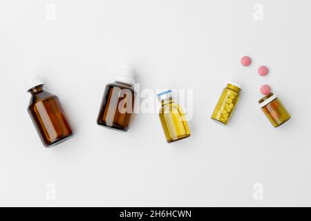 Petits flacons en verre avec médicaments sur fond blanc, à plat Banque D'Images