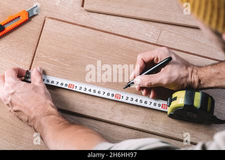 Installation de revêtements de sol stratifiés dans une salle ou un bureau.Parquet et outils.Travaux de construction et de décoration pour la finition de logements.Photo de haute qualité Banque D'Images