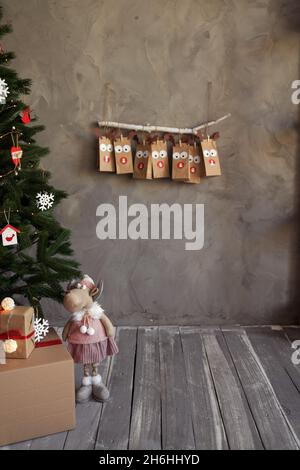 Noël artisanat emballage calendrier de l'Avent suspendu au mur, décoration de la chambre en hiver, fond gris. Banque D'Images