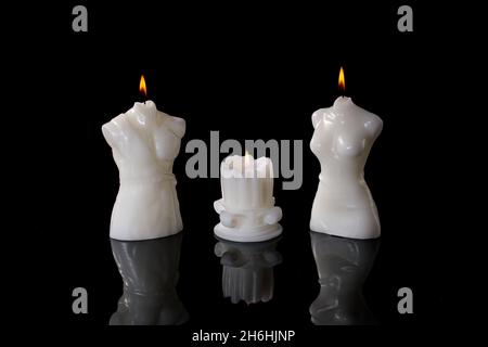 Trois bougies blanches, allumées sur fond noir. Banque D'Images