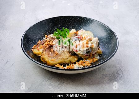 Concombre mariné à la pomme de terre bouillie et aux olives servi avec des tranches de poitrine de porc frites sur une assiette Banque D'Images