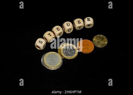 L'inscription sur les cubes, le mot TAXE en allemand sur les cubes de texture en bois avec des pièces de monnaie autour Banque D'Images