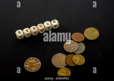 L'inscription sur les cubes, le mot TAXE en allemand sur les cubes de texture en bois avec des pièces de monnaie autour Banque D'Images