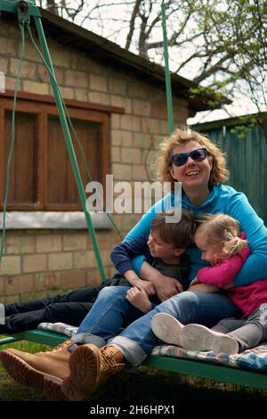 Grand-mère et ses deux petits-enfants s'amusent sur une balançoire, leur petit-fils et leur petite-fille aiment leur granny.Des hors-d'eux relaxants dans la campagne du grand-mère de Hou Banque D'Images