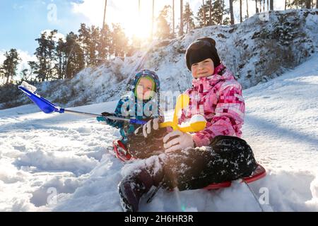 Portrait de deux adorables petits enfants joueurs portant une veste de neige chaude amusez-vous à jouer au parc en plein air par temps froid ensoleillé. Hiver Banque D'Images