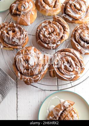 Petits pains à la cannelle faits maison et frais avec glaçage au sucre servis sur une grille de refroidissement.Vue de dessus, image verticale Banque D'Images