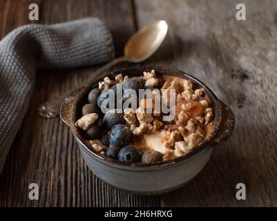 Petit déjeuner riche en protéines avec yaourt grec, puroseau de citrouille, purée de gâteaux de riz brun, myrtilles et cannelle.Servi isolé sur une table en bois. Banque D'Images