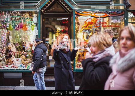 BUDAPEST, HONGRIE - 08 NOVEMBRE 2019: Fille de cheveux rouges appréciant le marché européen de Noël avec la foule de gens sur fond.Lumières floues et colorées Banque D'Images