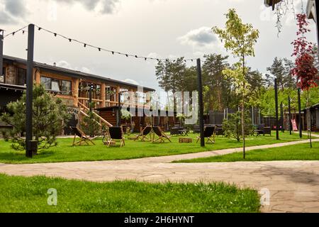 Pavillon d'alcôve en bois dans le club de golf de campagne de la banlieue.L'endroit pour les loisirs, les chaises longues.Les types sur le terrain de jeu rebondissant et sautant sur le t Banque D'Images