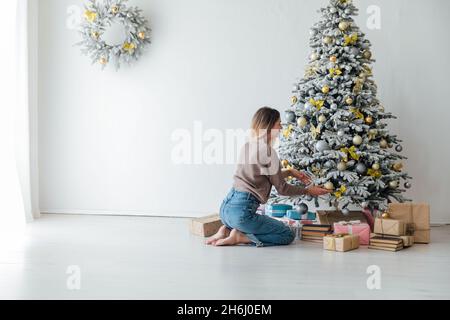 Belle femme décorent un arbre blanc de Noël nouvel an cadeaux décor Banque D'Images