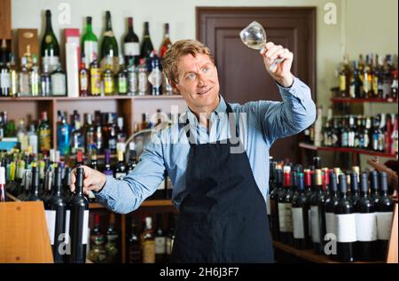 Homme travaillant dans une cave à vin tenant un verre de vin pour la dégustation Banque D'Images